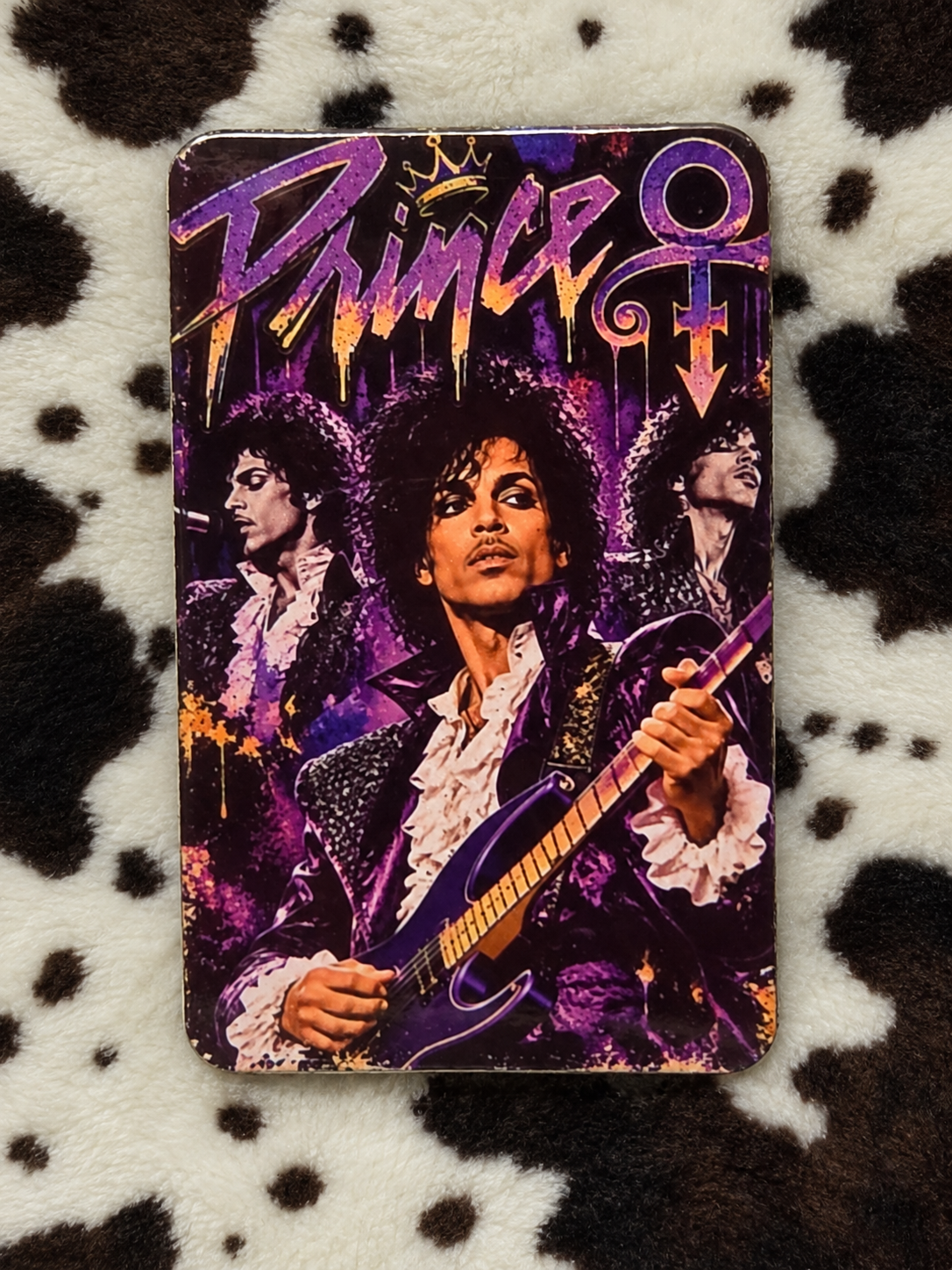 Prince purple guitar collage refrigerator magnet with rounded corners on a cow-print blanket