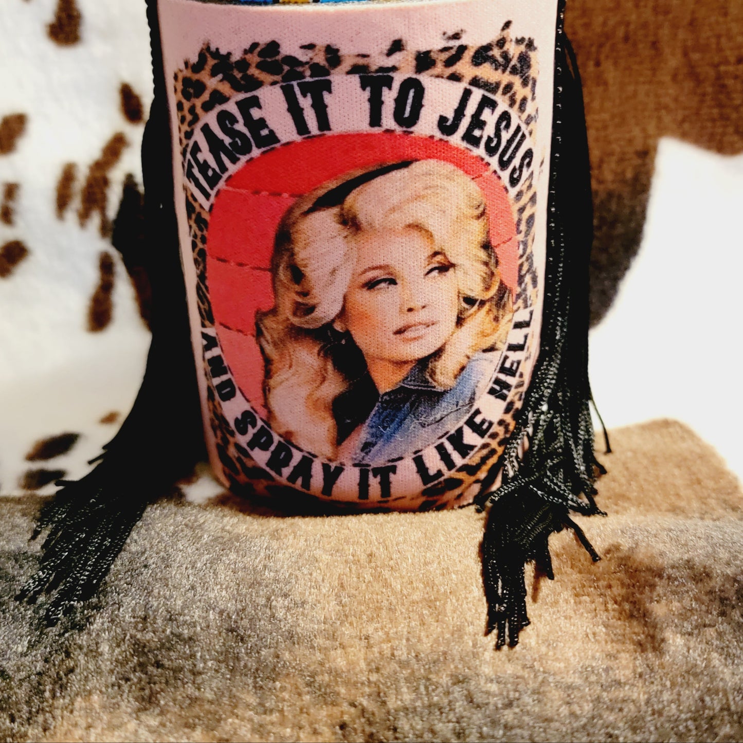 A pink neoprene can cooler koozie with a leopard print pattern and a design that reads 'TEASE IT TO JESUS' along with an image of a woman.
