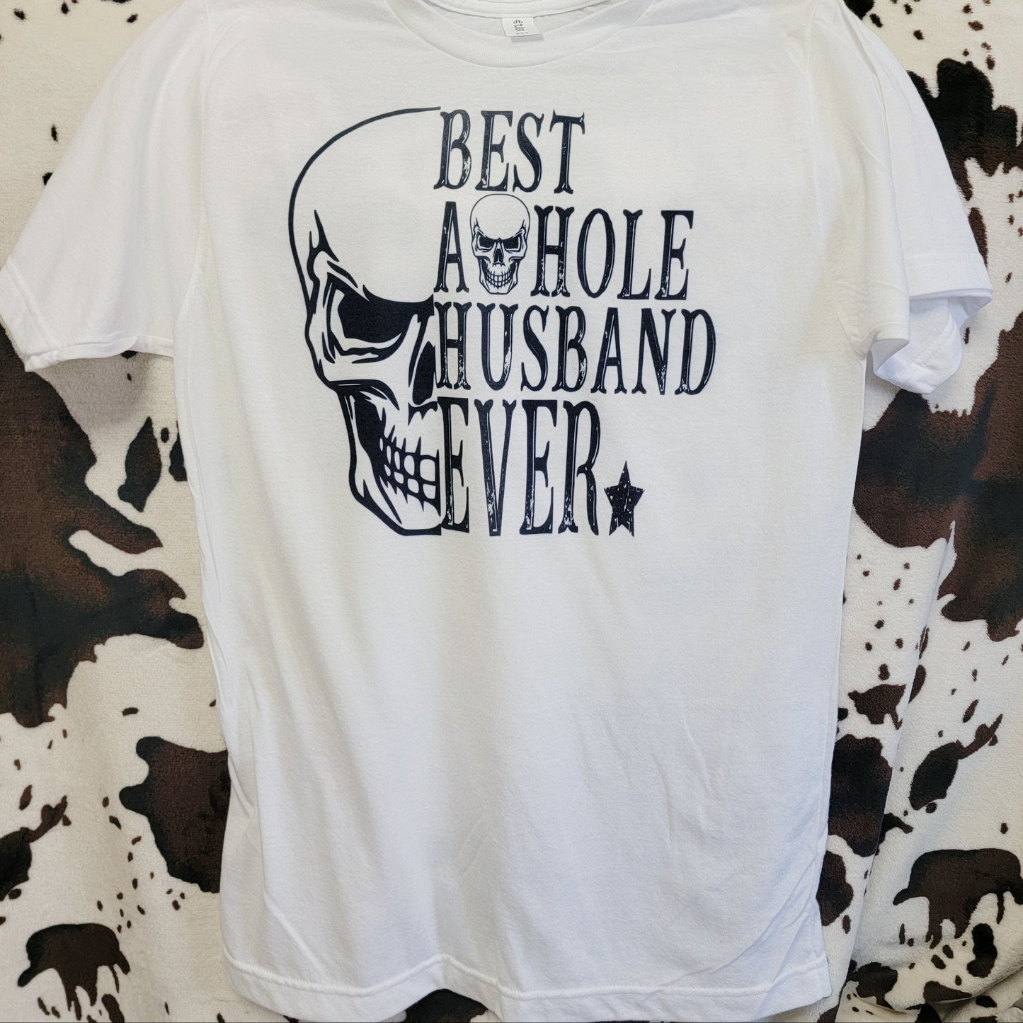 White t-shirt with black graphic and text on a cow print background