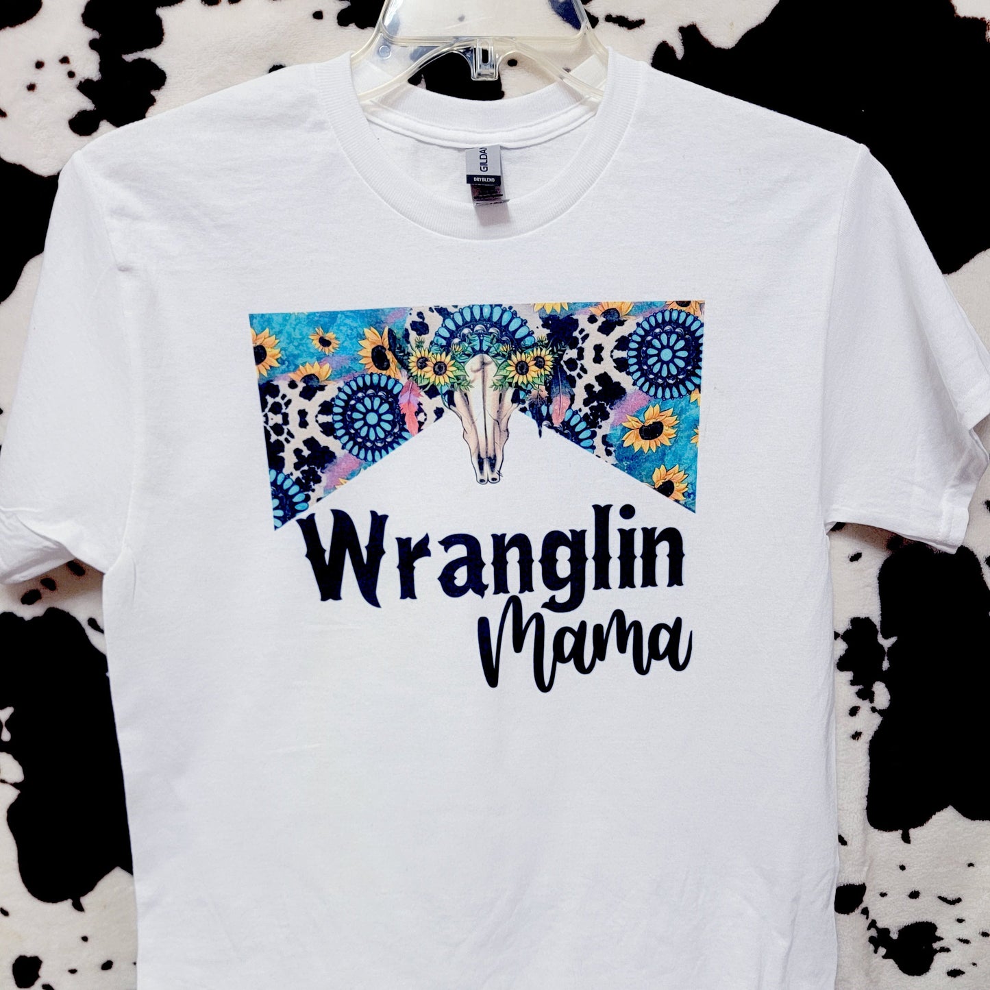 White t-shirt with 'Wranglin' Mama' text and floral design on a black and white patterned background