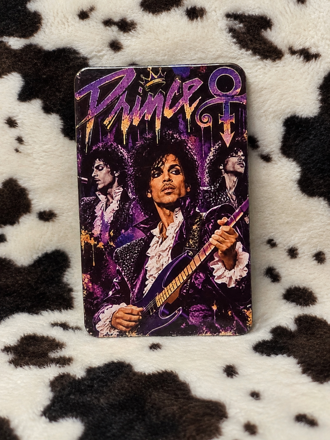 Prince purple guitar collage refrigerator magnet with rounded corners on a cow-print blanket
